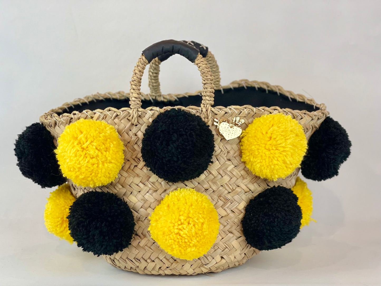 Basket with handmade yellow and black pom poms