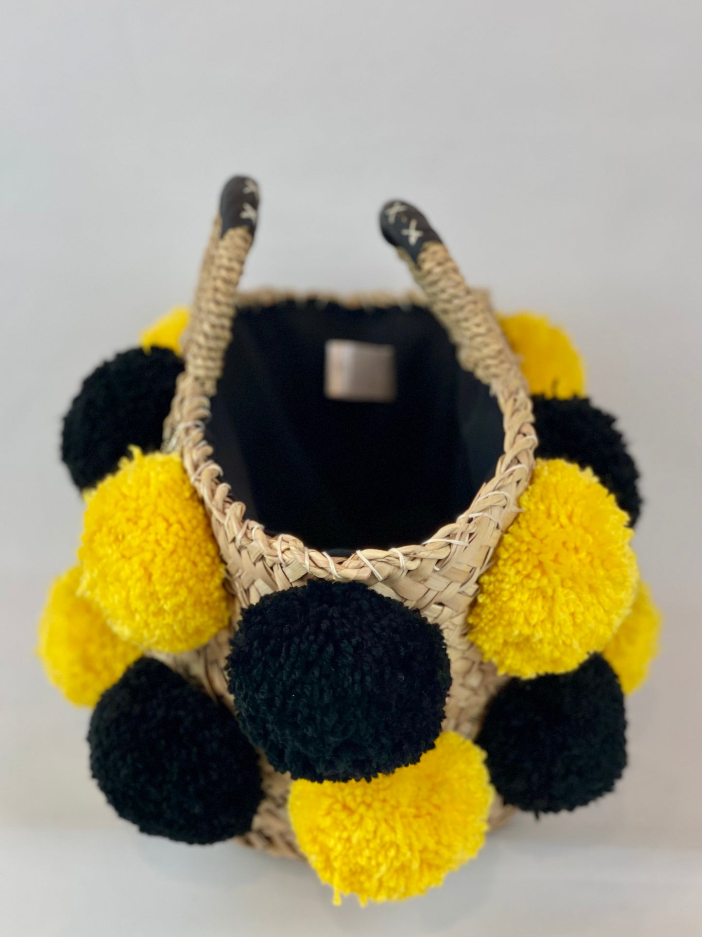 Basket with handmade yellow and black pom poms
