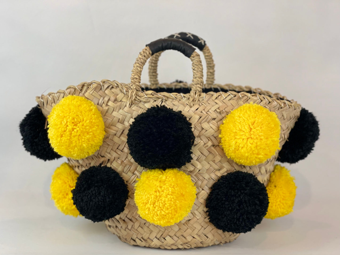 Basket with handmade yellow and black pom poms