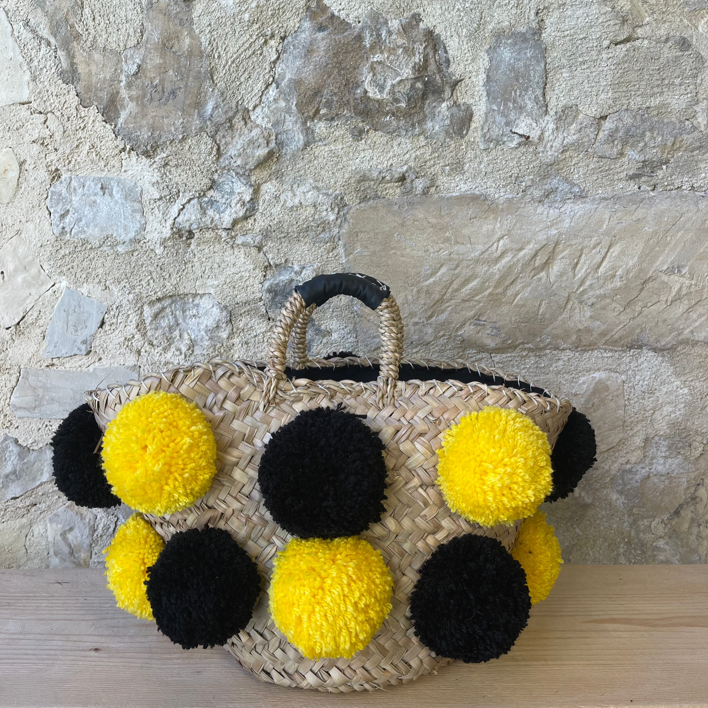 Basket with handmade yellow and black pom poms